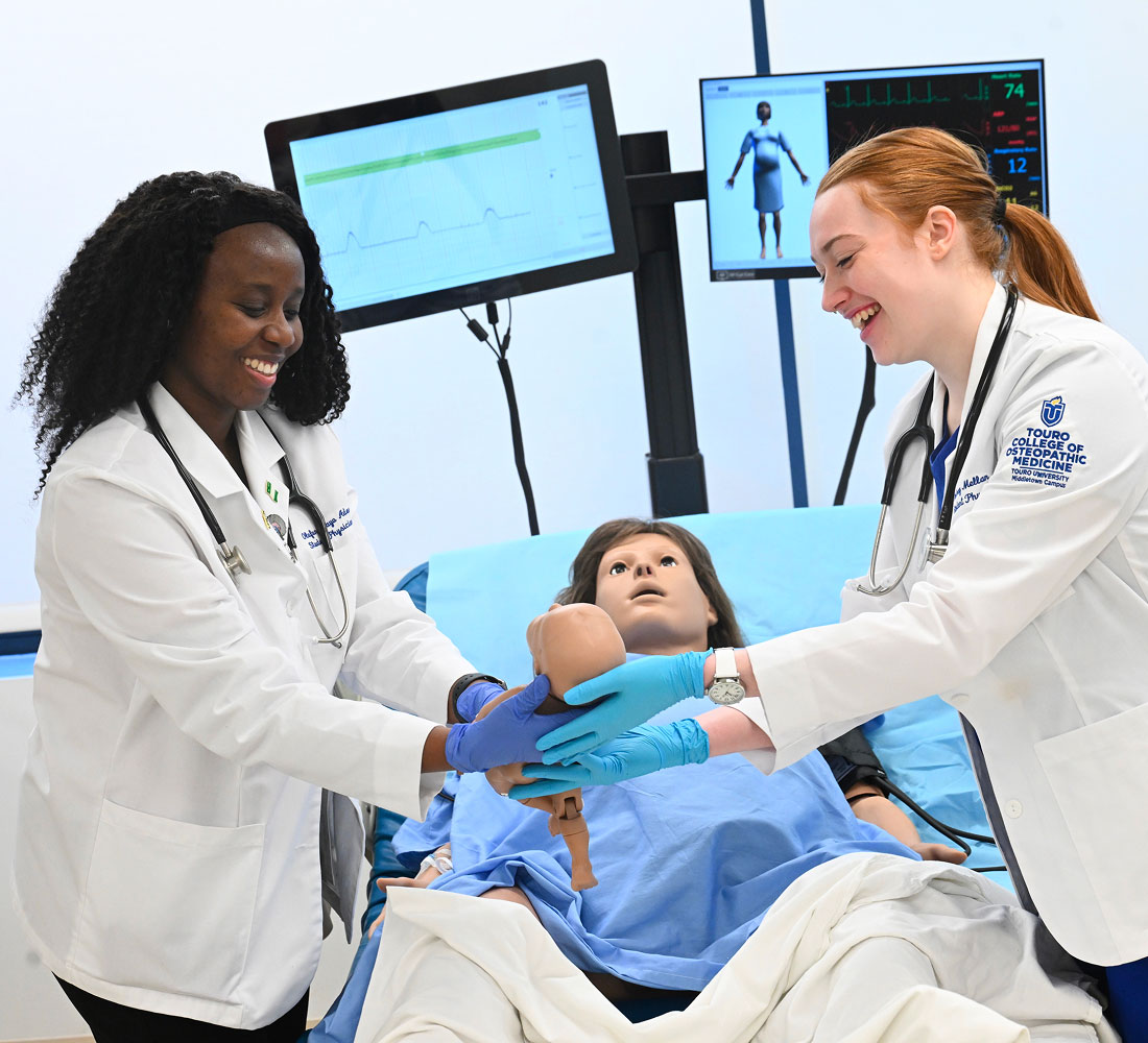 Two students working with birthing simulator mannikin