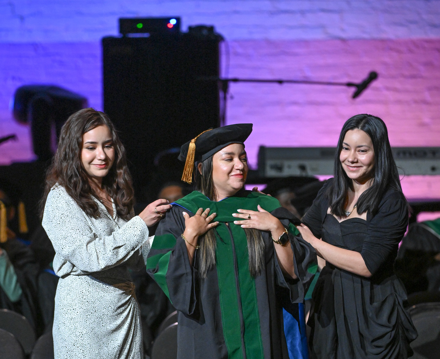 Drs. Jenifer and Mishelle Centeno-Gavica hood their sister Angela during TouroCOM Harlem\'s 2023 graduation ceremony.