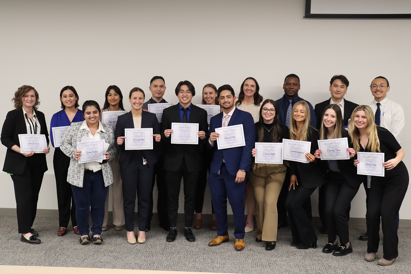 Image showing smiling TouroCOM Montana students proudly displaying their winning posters at the first annual Research Day and Poster Competition, showcasing their dedication to academic excellence and scientific discovery.