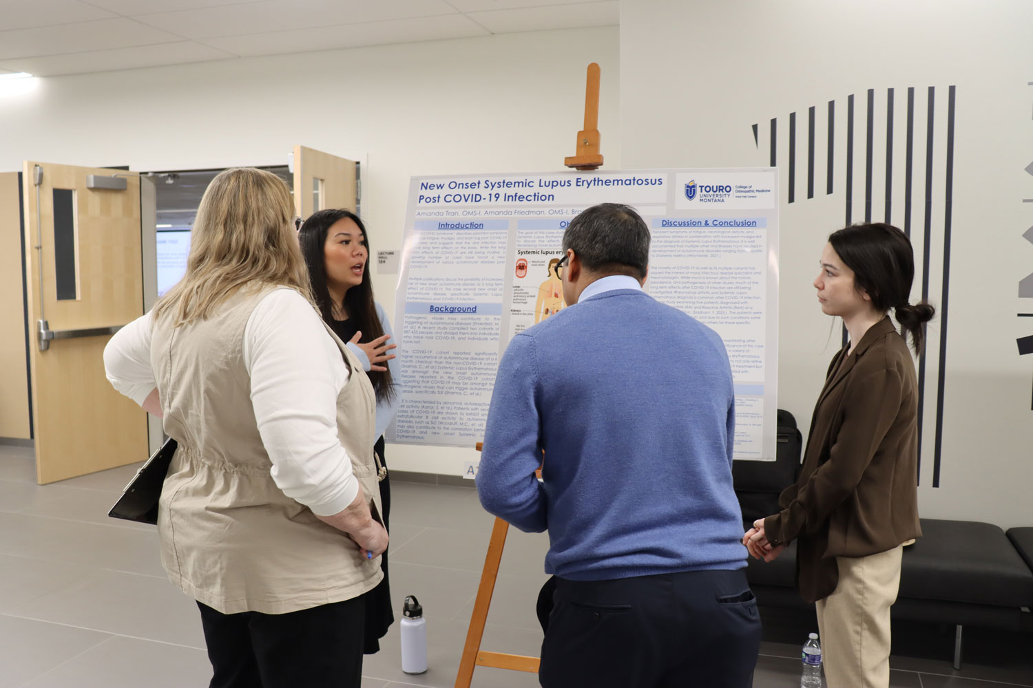 Students and faculty judges standing in front of posterboard