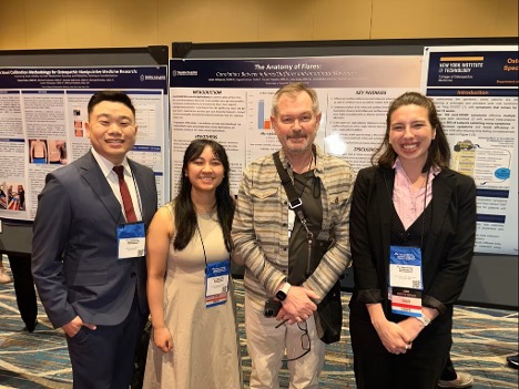 Three medical students and a faculty member by a poster during a medical convention.