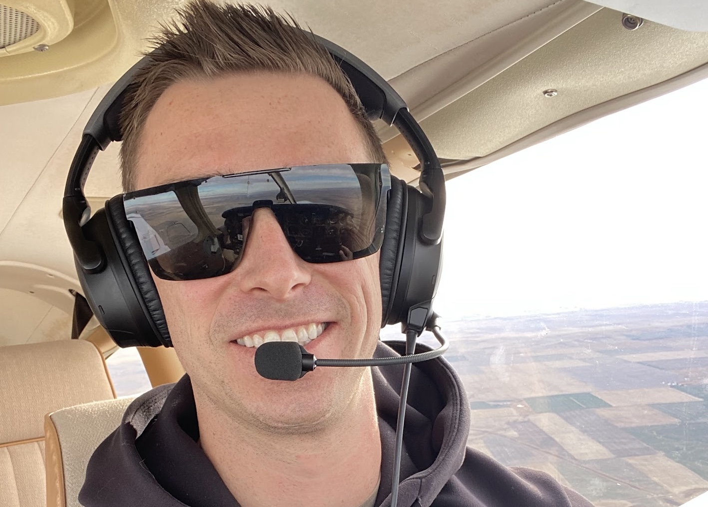 Medical student Colby Spongberg pilots a small airplane in flight, wearing a headset and monitoring the aircraft\'s instruments.