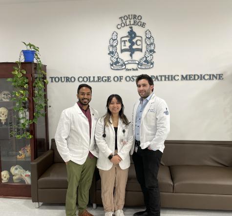 two male and one female medical students standing together smiling at camera