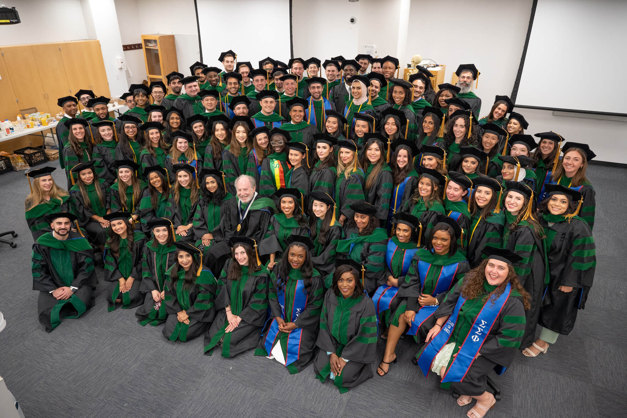 row of students in caps and gowns smiling into camera