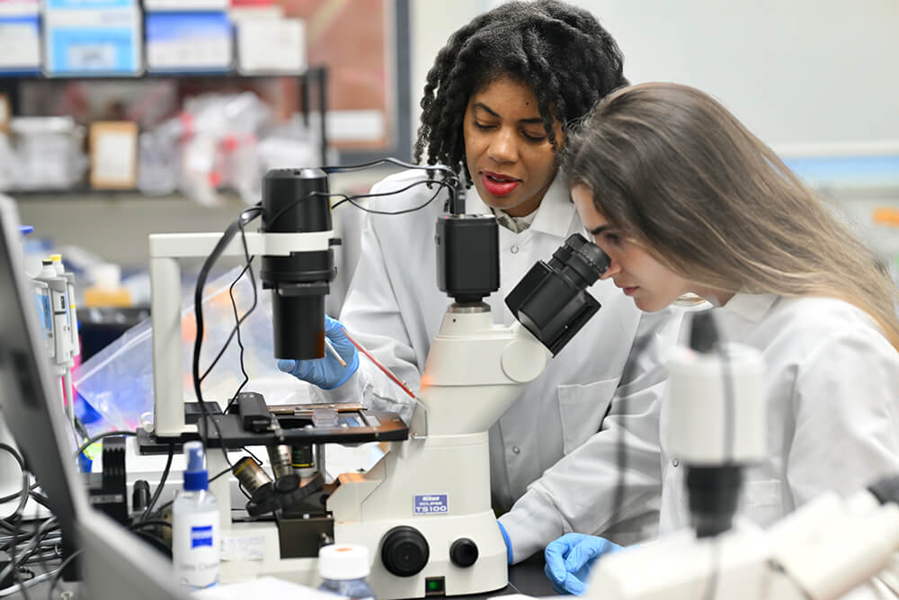 Dr. Kamilah Ali in lab with female student looking into microscope