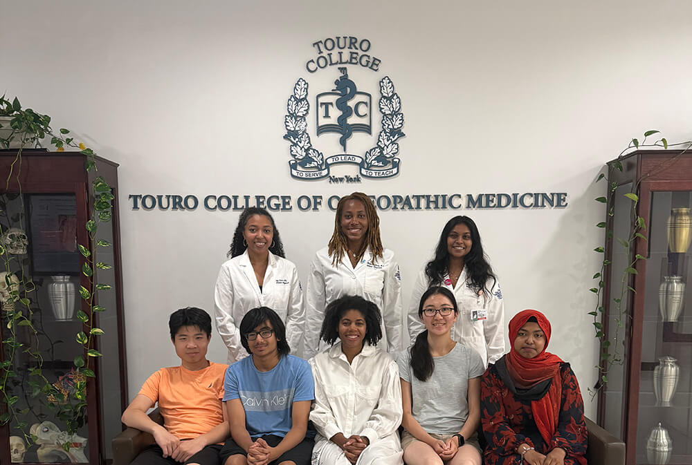 four high schools students seated with professor on bench in front of three standing medical students