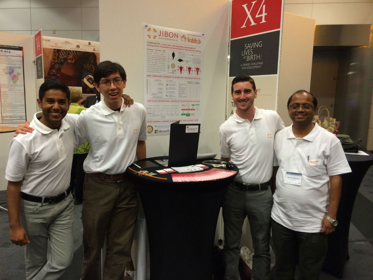 Four men stand by a booth. 