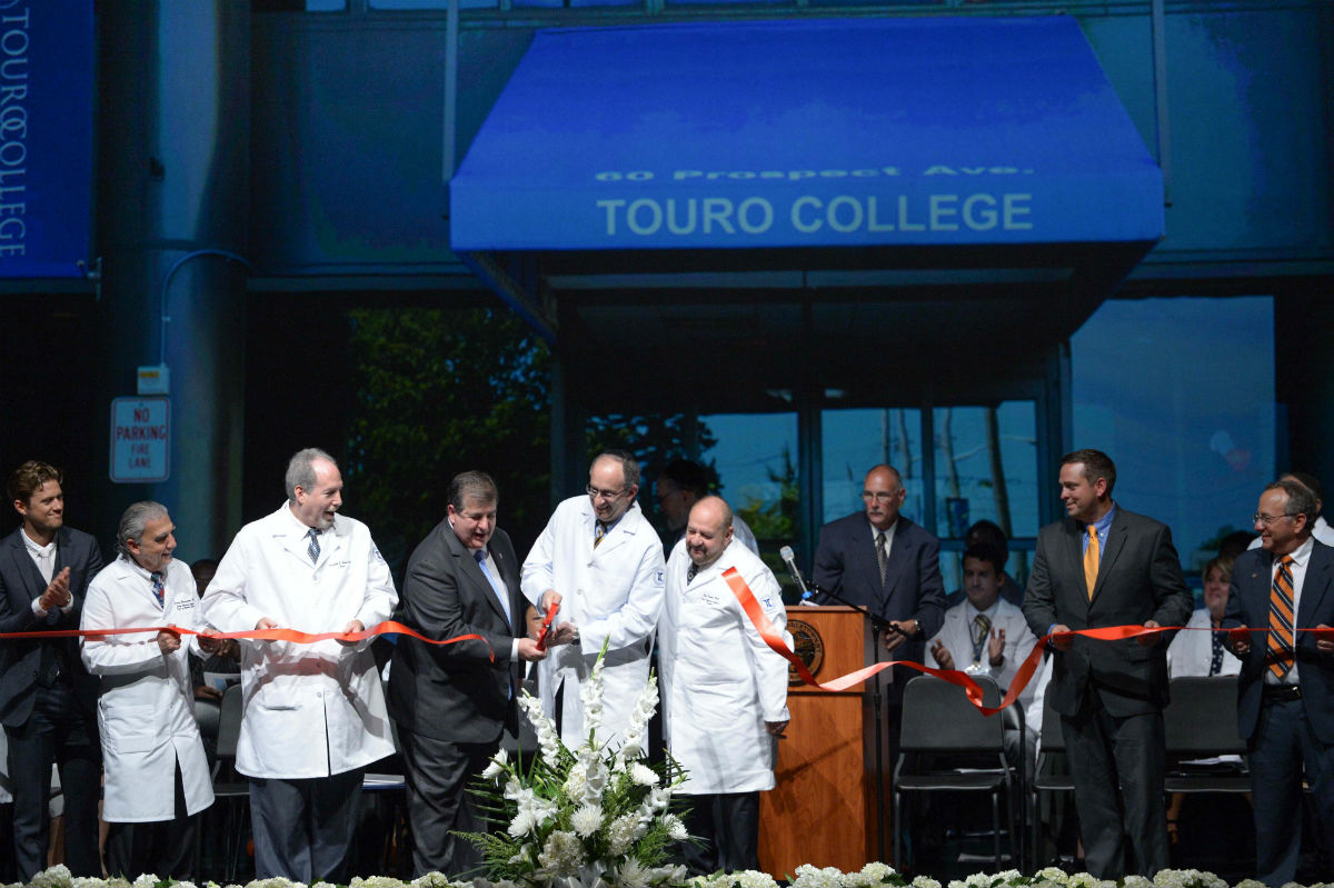 Several people participate in a ribbon cutting ceremony.