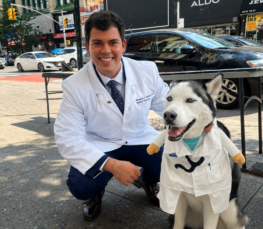 male medical student kneeling facing camera smiling with Husky by his side